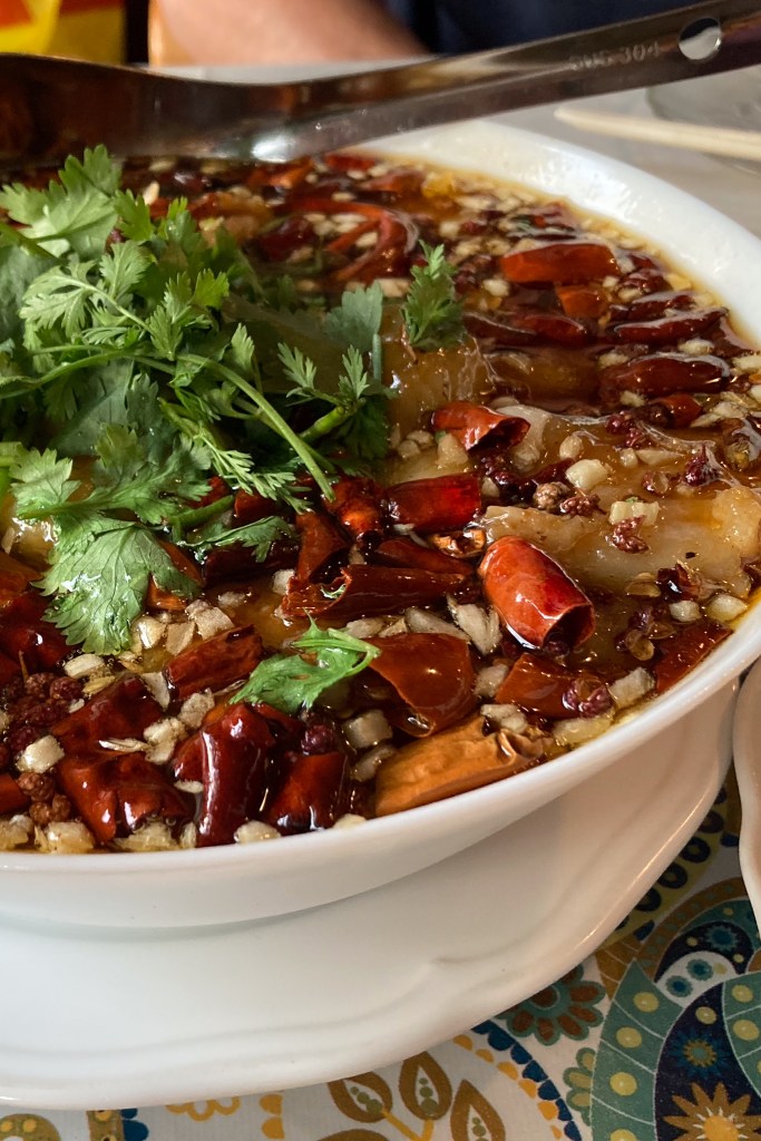 Bowl of Sichuan boiled fish in chili broth topped with cilantro